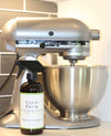 photo of a Red's Gone Green peppermint vanilla all natural cleaner standing next to a stand mixer