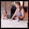 photot of a mother cleaning a marble countertop with a Red's Gone Green all natural cleaner